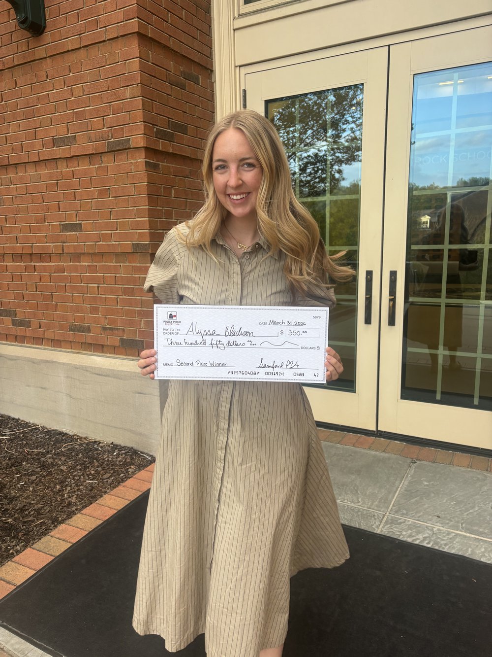Alyssa holding a second place award check at the Samford Policy Pitch Competition
